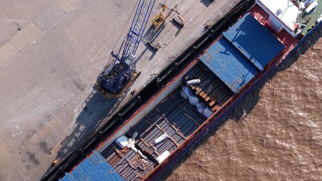 Aerial view of a cargo ship being loaded with steel beams by a large crane at PD Ports in Scunthorpe, England, United Kingdom.