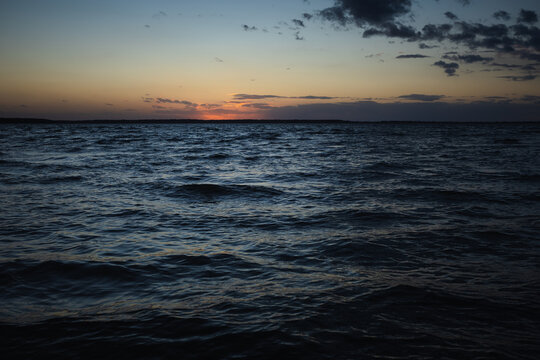 Sunset on the lake. Evening sky with beautiful clouds is reflected in the water of the lake