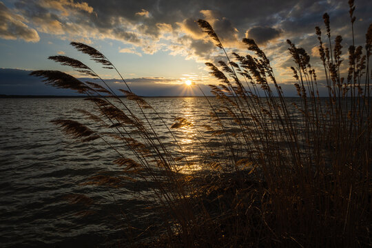 Sunset on the lake. Evening sky with beautiful clouds is reflected in the water of the lake
