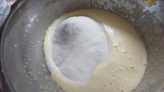 Adding flour to cake batter in a metal bowl close up