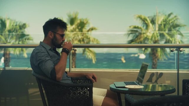 Freelancer Drinking CoffeeAt Tropical Resort Terrace During Remote Work. Digital Nomad Office