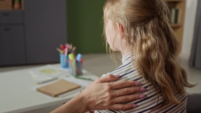 Close up on mothers hand reassuring preteen daughter with supportive touch on shoulder during parent child therapy session at home