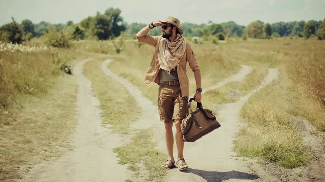 Traveler Walking With Bag On Dusty Road In Field. Adventurer Wandering In Wilderness