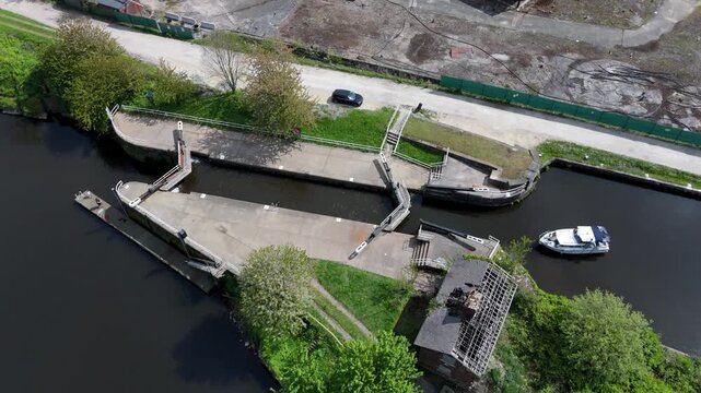 Aerial view of a canal lock system with a white boat and historic stone walls in Knottingley, England, United Kingdom.