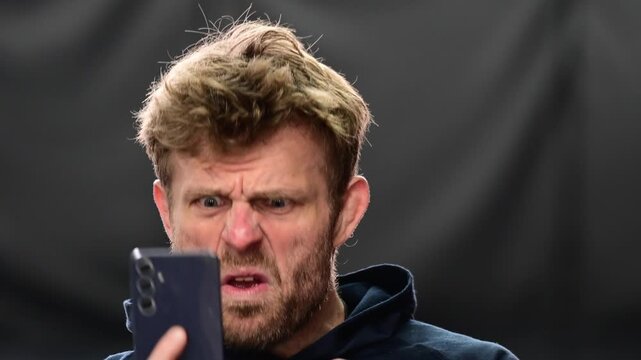 Social media culture, man looking at his phone with array of emotions, close up on the face isolated portrait shot, real time video authentic, white people. Throwing the phone away in shock
