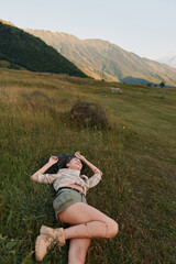 Naklejka premium Relaxed woman lying in a field with mountains in the background, casual countryside vibe, sunlit calm, carefree lifestyle moment.