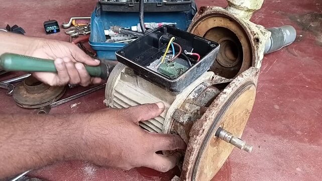 Technician Striking The Rear Of The Rotor Shaft With A Hammer To Remove The Front End Plate Of An Electric Motor