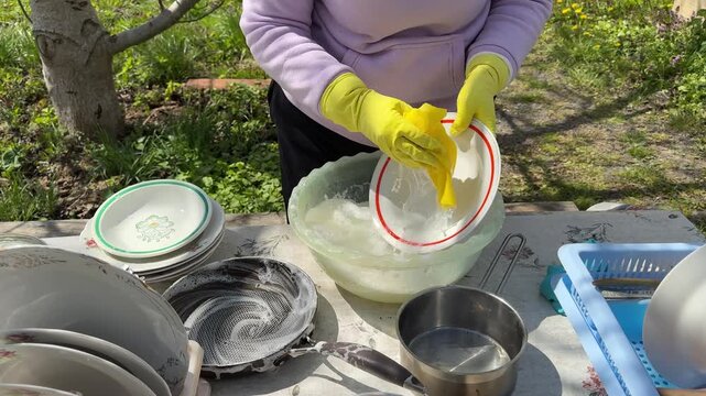 close up of old woman hands washing dishes outdoors, simple atmosphere with traditional kitchen utensils, depicting daily activities and rural life