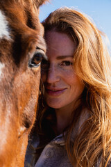 Fototapeta premium Woman smiling bonding with her horse outdoors