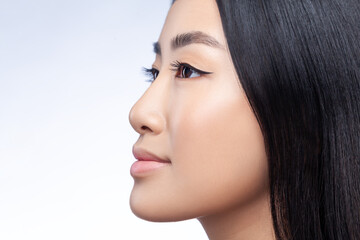 Profile portrait of gentle beautiful Asian young woman with long smooth straight dark hair and soft smile looking away with relaxed expression isolated on gray background © khosrork
