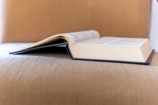Open book resting on a soft, brown couch invites quiet moments of reflection and discovery in a cozy space
