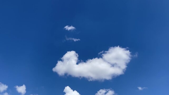 Azure Sky's Embrace: Witness the airy dance of fluffy clouds gracefully drifting against a vast canvas of a bright, clear blue sky. A moment of tranquility.