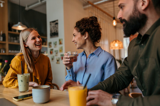 Friends talking and laughing enjoying drinks in a cafe