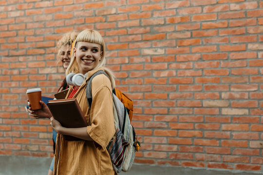 Happy students walking on campus with coffee and books