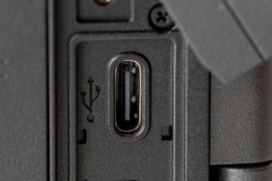 Extreme close-up of a modern USB-C port on a professional camera body, detailed macro shot of universal serial bus TYPE-C connector with symbol on black plastic surface