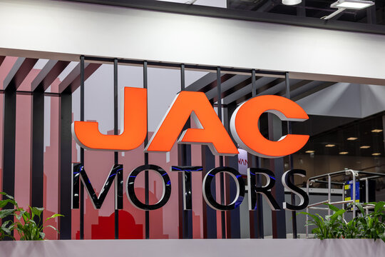 JAC MOTORS brand logo signage at a commercial automotive exhibition stand. Large orange and black corporate lettering on a decorative background. Astana, Kazakhstan - May 30, 2024