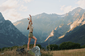 A woman in casual clothes stands on a rock throwing a ball in a mountain landscape. The scene shows active lifestyle and outdoor recreation in nature. © SHOTPRIME STUDIO