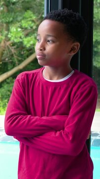 Vertical video: Turning child in red shirt smiling at sliding glass door as camera zooming to pool