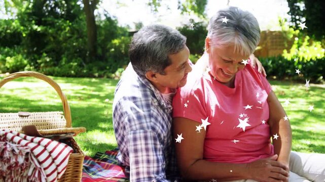 Senior pair sitting blanket woman tapping laptop man leaning in AR stars drifting over couple