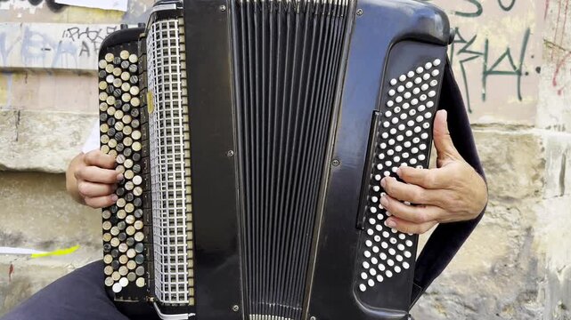 Male hands of musician playing the accordion at urban street. The detailed view highlights texture of instrument, capturing rhythm, tradition, and the expressive character of live music performance