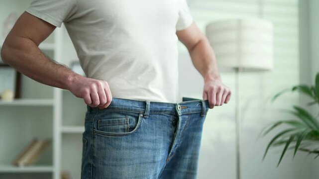 Man Pulling Loose Jeans Waistband to Show Weight Loss and Diet Success