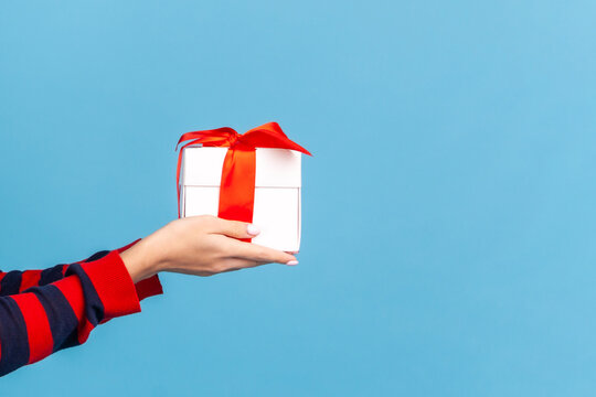 Side view of angel holding gift box for charity or holy holiday celebration and support for community isolated over blue background with copy space