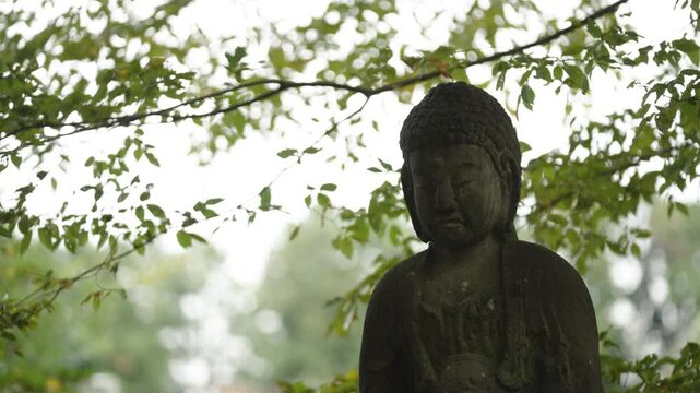 Stone Jizo Bosatsu Statue Wearing Red Bib in a Japanese Temple Garden