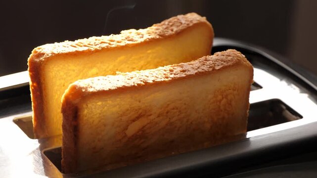 Toast browning in toaster, morning kitchen scene. Freshly toasted bread creates warm atmosphere, ideal for breakfast. Enjoy delicious start to day with perfect toast.