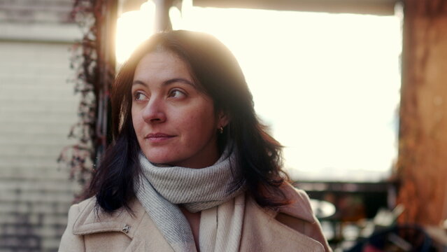 Woman in beige coat and scarf looking thoughtfully outdoors, woman with natural expression in afternoon light during peaceful winter outing