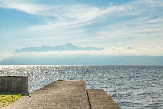 Jet&eacute;e en b&eacute;ton s'avan&ccedil;ant sur le lac L&eacute;man avec scintillement du soleil &agrave; Saint-Prex, Suisse