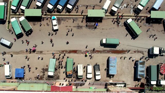 Aerial view of a bustling bus station with rows of green and white vans and people walking between vehicles in Wewak, East Sepik Province, Papua New Guinea.