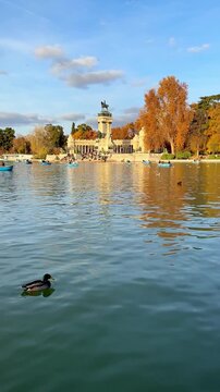 Landscape of the Retiro Park in Madrid, with the monument to King Alfonso XII and boats on the lake