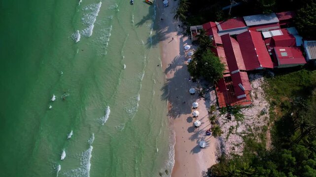 Aerial video of the amazing emerald water white sand Sao Beach with lively water sports, tourists, cabanas and sun umbrellas, beach bar and parasailing. Hot sunny day with long waves on Phu Quoc Islan