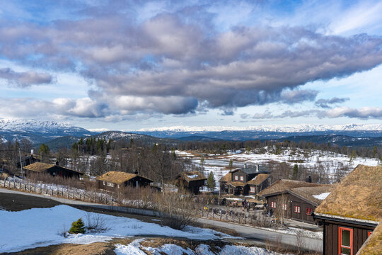  Amazing view of Norwegian mountains. Stunning landscape with traditional wooden houses and snowing tops on the horizon.