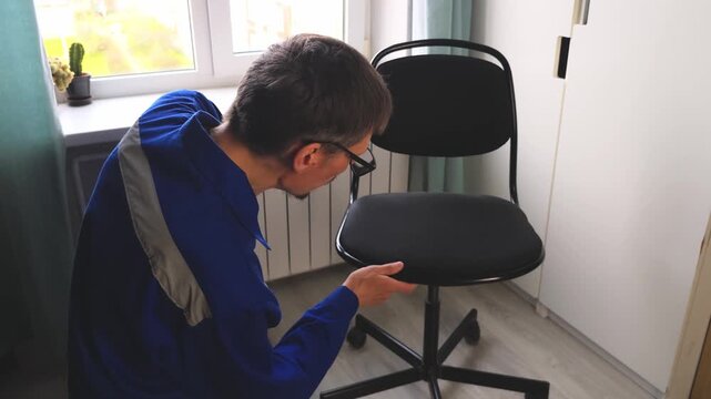 Master repairs an office chair in a room during the day