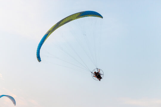 A paraglider with a motorized unit soars gracefully through the clear blue sky, showcasing the thrill of aerial adventure