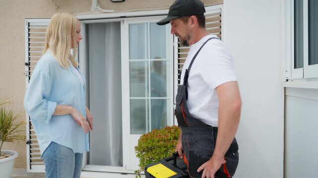 Female client talking with male contractor about home repair job. Professional consultation, planning maintenance work and discussing project details at residential property.