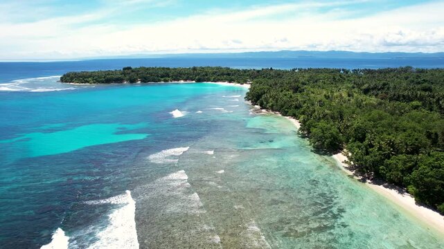 Aerial view of Mushu Island featuring turquoise coral reefs, white sand beaches and dense tropical jungle in Wewak District, East Sepik Province, Papua New Guinea.