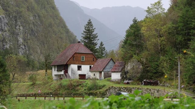 car driving in the rain past a small house in the soca river valley of slovenia (europe european travel tourism destination) julian alps drive motor vehicle automobile