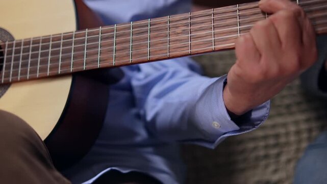 An elderly man playing the guitar, his fingers on the fretboard close up