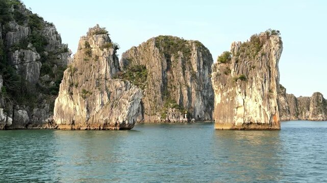 Limestone karst pillars rising from calm turquoise sea waters in Halong Bay Vietnam, travel adventure