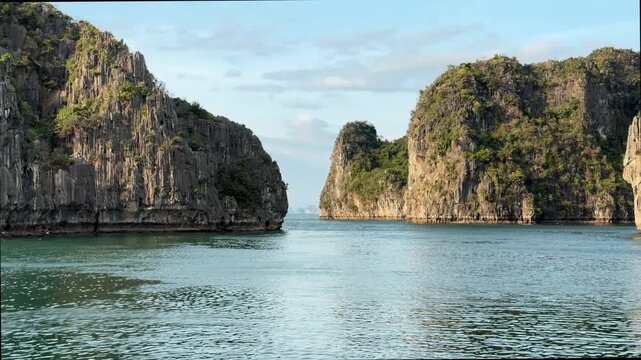 Limestone karst pillars rising from green sea in Halong Bay Vietnam, tranquil tropical seascape, serene nature travel destination, exotic bay scenery