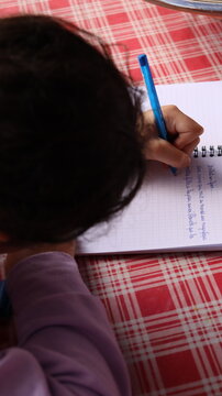 Child writing a story in spiral notebook at home, handwriting practice and creative writing concept for school homework