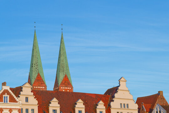 Historic European architecture with red roofs and green church spires under blue sky