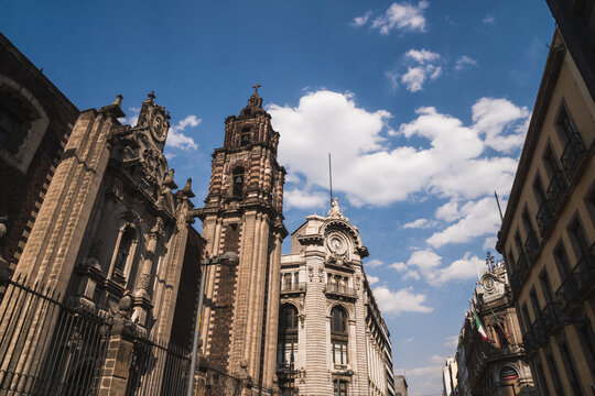 Historic architecture of Mexico City with ornate buildings under a bright blue sky and scattered clouds during daytime