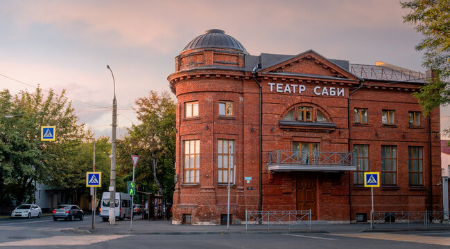 Vladikavkaz, North Ossetia - Alania, Russia - 08 18 2025: The historic red brick Sabi Puppet Theater building at sunset with city street and traffic signs