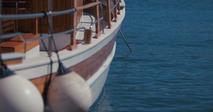 Close up of a wooden boat moored on calm water with boat fenders hanging beside the hull in Rovinj, Croatia.