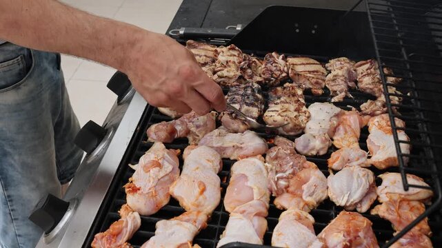 A man flips meat while it's being grilled. High quality 4k footage