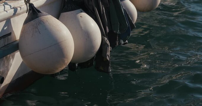 Close-up of boat fenders hanging beside a moored fishing boat on water at harbor in Rovinj, Istria, Croatia.
