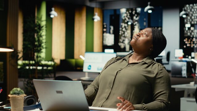 African american woman at the firm office in deep concentration, pondering the implications of a decision. Using laptop as she applies rational thinking and intuition to solve a dilemma. Camera B.